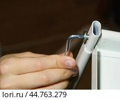 Closeup of a hand screwing Allen key. Furniture assembling. Two parts (pipe and shelf) are screw together to get the bookcase. Using the hex wrench. Стоковое фото, фотограф YuryKara / Фотобанк Лори
