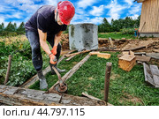 To lower concrete ring into pit during septic tank installation, worker uses winch. Стоковое фото, фотограф Владимир Григорьев / Фотобанк Лори