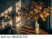 Branches with golden autumn leaves in a ceramic vase on a wooden table by the window. The concept of home comfort. Autumn decor for Halloween. Стоковое AI-изображение, AI-художник Photojuli / Фотобанк Лори
