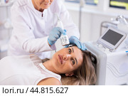 Young woman experiencing facial cryotherapy procedure using ice hammer. Стоковое фото, фотограф Яков Филимонов / Фотобанк Лори