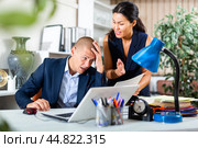 Upset office employe looking on laptop with disgruntled female manager. Стоковое фото, фотограф Яков Филимонов / Фотобанк Лори