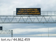 Система информирования. Дорожное информационное табло "Соблюдайте ПДД Ведется фотовидео фиксация нарушений" над дорогой. Стоковое фото, фотограф Ekaterina M / Фотобанк Лори