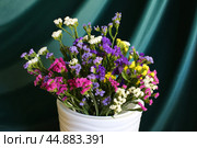 Bouquet of multicolored flowers in a vase (Limonium sinuatum, Statice sinuata) on a green background. Стоковое фото, фотограф Ирина Вершинская / Фотобанк Лори