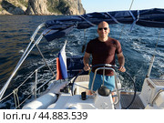 Капитан яхты у скал мыса Айя в окрестностях Балаклавы, Севастополь, Крымский полуостров, Россия (2021 год). Редакционное фото, фотограф Free Wind / Фотобанк Лори