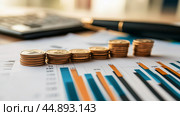 Financial analysis with coins and charts on a desk showcasing investment trends and calculations. Стоковое AI-изображение, AI-художник Сергей Толмачёв / Фотобанк Лори