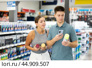 Spouses scans product QR code with phone on color aerosol in paint and vanish store. Стоковое фото, фотограф Яков Филимонов / Фотобанк Лори