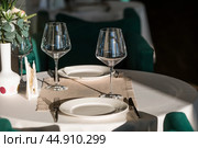 Stylish table setting. Glass glasses, plates, cutlery on the table. Wedding service, reception at the dining table. A birthday, a baptism, a festive event. Стоковое фото, фотограф Photojuli / Фотобанк Лори