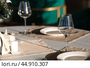 Stylish table setting. Glass glasses, plates, cutlery on the table. Wedding service, reception at the dining table. A birthday, a baptism, a festive event. Стоковое фото, фотограф Photojuli / Фотобанк Лори