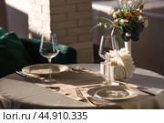 Stylish table setting. Glass glasses, plates, cutlery on the table. Wedding service, reception at the dining table. A birthday, a baptism, a festive event. Стоковое фото, фотограф Photojuli / Фотобанк Лори