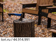 Eco-friendly, stylish barbecue area and wooden chairs for relaxing by the campfire. An axe will be stuck into a wooden log. Chopping firewood. Стоковое фото, фотограф Photojuli / Фотобанк Лори