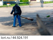 An old man sweeps asphalt on the street with a homemade broom. Стоковое фото, фотограф Татьяна Степанищева / Фотобанк Лори