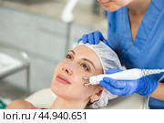 Adult woman cosmetologist doing microcurrent procedure to young woman. Стоковое фото, фотограф Яков Филимонов / Фотобанк Лори