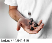Close-up of person tossing polyhedral dice against a white background. Стоковое фото, фотограф Lamina Akulova / Фотобанк Лори
