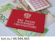 Пенсионное удостоверение МВД России и калькулятор лежат на денежных купюрах. Стоковое фото, фотограф Сергей Овчинников / Фотобанк Лори