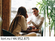 Man and Woman Sitting at Table Talking. Стоковое фото, фотограф Сергей Толмачёв / Фотобанк Лори