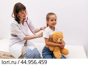 Happy beautiful female doctor holding stethoscope and doing lungs check up to little child. Smiling pediatrician examine her patient's respiration during routine checkup at modern pediatric clinic. Стоковое фото, фотограф Ирина Михайличенко / Фотобанк Лори