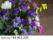 Bouquet of multicolored flowers in a vase (Limonium sinuatum, Statice sinuata) on a green background. Стоковое фото, фотограф Ирина Вершинская / Фотобанк Лори