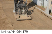 Worker operating a vibrating soil compactor used to compact soil in preparation for paving stones. Construction and renovation. Стоковое видео, видеограф Мария Зубарева / Фотобанк Лори