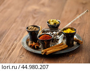 Oriental spice set - coriander, red pepper, turmeric, cinnamon, star anise, rosemary various seasonings in metall cups, on brown wooden table, side view, mcro, selective focus. Стоковое фото, фотограф Natalia Gdovskaia / Фотобанк Лори
