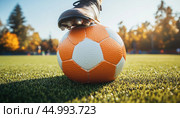 Soccer player holding ball on cleat with autumn colors in background. Стоковое AI-изображение, AI-художник Юрий Поздников / Фотобанк Лори