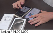 A man is transferring data from the old iPhone 7 Plus to the new iPhone 15 Pro Max. Редакционное видео, видеограф Vadzim Yakubovich / Фотобанк Лори