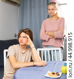 Offended teenager sitting at home table after disagreements with mom. Стоковое фото, фотограф Яков Филимонов / Фотобанк Лори