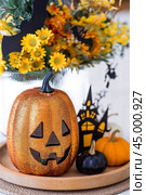 A vase of flowers, pumpkins and a scary castle with a witch on the background of a Scandi-style white kitchen interior. The concept of home and comfort. Autumn decor for Halloween. Стоковое фото, фотограф Photojuli / Фотобанк Лори