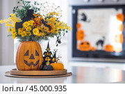 A vase of flowers, pumpkins and a scary castle with a witch on the background of a Scandi-style white kitchen interior. The concept of home and comfort. Autumn decor for Halloween. Стоковое фото, фотограф Photojuli / Фотобанк Лори