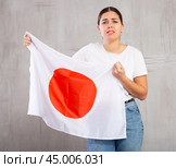 Sad young woman holding Japan flag against unicoloured background. Стоковое фото, фотограф Яков Филимонов / Фотобанк Лори