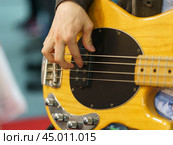 Photography of the musician plays the bass guitar. He picks the strings, clamps the strings on the fretboard. Стоковое фото, фотограф YuryKara / Фотобанк Лори