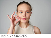 Young Woman Making a Hush Gesture on gray background in studio. Стоковое фото, фотограф Сергей Толмачёв / Фотобанк Лори