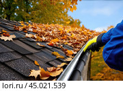Worker cleans roof of house from autumn leaves, close-up. Maintenance of roofs and gutters of houses. Стоковое AI-изображение, AI-художник Коханова Наталья / Фотобанк Лори