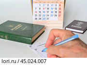 Мужская рука записывает имена усопших в церковную записку о поминовении. Редакционное фото, фотограф Владимир Литвинов / Фотобанк Лори