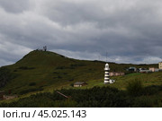 Маяк в лучах солнца в горах на фоне пасмурного неба. Стоковое фото, фотограф Алена Горбунова / Фотобанк Лори