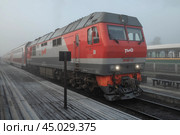 Российский пассажирский тепловоз ТЭП-70БС с двухэтажным поездом Москва-Петрозаводск на станции Сортавала туманным октябрьским утром. Редакционное фото, фотограф Виктор Карасев / Фотобанк Лори