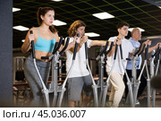 Group of people of different ages train on elliptical trainers steppers. Стоковое фото, фотограф Яков Филимонов / Фотобанк Лори