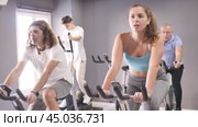 Concentrated young fit girl working out on stationary bicycle in gym. Healthy active lifestyle concept. Стоковое видео, видеограф Яков Филимонов / Фотобанк Лори