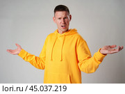 Portrait of confused clueless man on gray background in studio. Стоковое фото, фотограф Сергей Толмачёв / Фотобанк Лори
