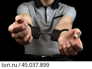 Hands of the criminal are bound by handcuffs close-up on a black background. Стоковое фото, фотограф Дмитрий Кобзев / Фотобанк Лори