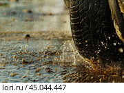 Car tire is driving through a puddle on a rainy day. Стоковое AI-изображение, AI-художник Иван Рябоконь / Фотобанк Лори