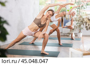 Young woman doing Utthita Parsvakonasana asana in yoga studio. Стоковое фото, фотограф Яков Филимонов / Фотобанк Лори