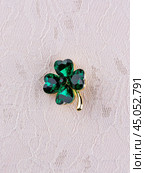 Close-up bright green beautiful clover brooch in crystals on light background. Стоковое фото, фотограф Виталий Сова / Фотобанк Лори
