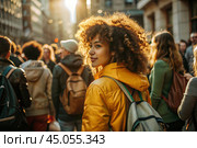 Portrait of a curly-haired beautiful mulatto traveler in a yellow jacket and with a backpack in the city. Traveling alone is a lifestyle. A young tourist is enjoying his autumn vacation. Стоковое AI-изображение, AI-художник Photojuli / Фотобанк Лори