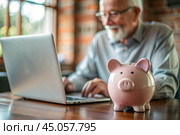 Pension. Saving money. Savings. Piggy bank in the form of a pig in close-up, Calculating the total amount of the budget. An elderly man learns how to interact with a laptop in online payments, finance, loans, transactions. Стоковое AI-изображение, AI-художник Photojuli / Фотобанк Лори
