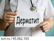 Слово ДЕРМАТИТ написано на белой бумаге, которую держит в руках врач. Стоковое фото, фотограф Жанна Гапанович / Фотобанк Лори
