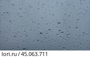 Heavy raindrops tapping on the window pane. Raindrops flowing down the window pane during a downpour. Rainy weather. Капли дождя стучат по стеклу во время ливня. Стоковое видео, видеограф Ольга Петрова-Апостолова / Фотобанк Лори