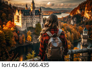 A traveler girl with a backpack on the background of a huge castle in the autumn forest in the mountains. The guy travels and enjoys life and the environment. Tourism. Стоковое AI-изображение, AI-художник Photojuli / Фотобанк Лори
