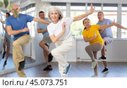 Elderly woman practicing Tai Chi with group in training room. Стоковое фото, фотограф Яков Филимонов / Фотобанк Лори
