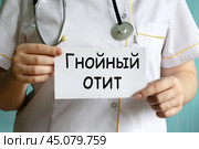 Врач держит белый лист с словами ГНОЙНЫЙ ОТИТ. Стоковое фото, фотограф Жанна Гапанович / Фотобанк Лори
