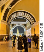 SAINT PETERSBURG, RUSSIA-December 25, 2023: People walking along Bolshaya Morskaya Street decorated with garlands and taking pictures of Christmas tree through arch of General Staff Building in winter. Редакционное фото, фотограф Виктория Катьянова / Фотобанк Лори